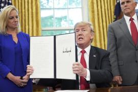 Watched by Homeland Security Secretary Kirstjen Nielsen and Vice President Mike Pence, U.S. President Donald Trump shows an executive order on immigration that he signed in the Oval Office of the White House on Wednesday in Washington. Mandel Ngan/AFP/Getty Images